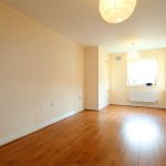 Empty room with wooden flooring and pendant lights.