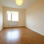 Empty room with wooden flooring and light fixture.