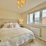 Bright bedroom with large window and cosy bed.