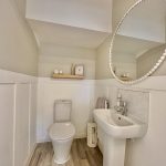 Modern bathroom with toilet, sink, and round mirror.