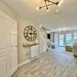 Spacious living room with garden view and clock.