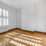Empty room with wooden floor and shuttered window.