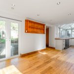 Modern kitchen with wooden floor and glass doors.