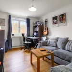 Cosy living room with desk and guitar decor.