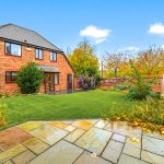 Red brick house with garden and patio.