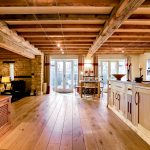 Spacious rustic kitchen with wooden beams and floor.