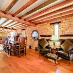 Spacious rustic living room with stone walls and beams.