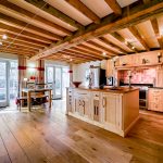 Spacious rustic kitchen with wooden beams and flooring.