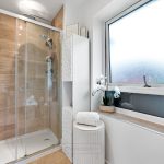 Modern bathroom with glass shower and window.