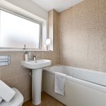 Modern bathroom with bathtub and pedestal sink.