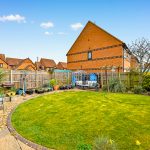 Suburban garden with lawn, patio, and potted plants.