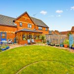 Spacious garden with patio and brick house.