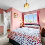 Cosy pink bedroom with double bed and window view.