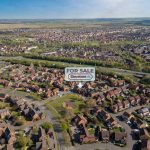 Aerial view of houses with 'For Sale' sign.