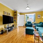 Bright living room with teal sofas and wooden floor.