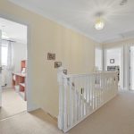 Bright upstairs hallway with open doors, carpeted flooring.