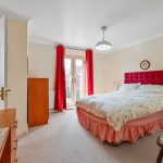 Bright bedroom with red curtains and double bed.