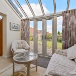 Cosy conservatory with garden view and glass ceiling.