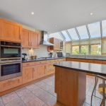 Modern kitchen with wooden cabinets and large windows.