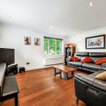 Modern living room with piano and black leather sofas.