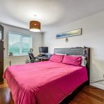 Modern bedroom with pink bedding and computer desk.
