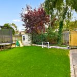 Backyard with trampoline, slide, and football goal.
