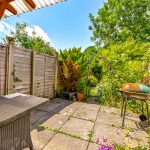 Sunny patio with barbecue and garden view.