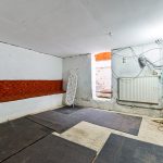 Empty basement room with exercise mats and ironing board.