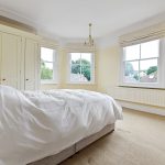 Bright bedroom with double bed and large windows.
