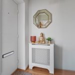 Hallway with mirror, Buddha statue, plant and lamp.