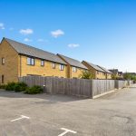 Modern residential street with brick houses and parking.