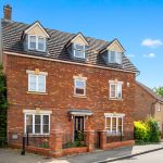 Three-storey brick house on sunny street.