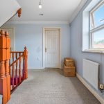 Carpeted landing with wooden staircase and wicker baskets.