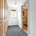 Bright hallway with wardrobes leading to bathroom.