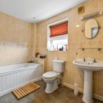 Modern bathroom with bathtub, sink, and mirror.