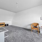 Minimalist attic room with carpet and wicker chair.
