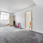 Spacious attic room with grey carpet and chair.