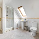 Spacious attic bathroom with shower and skylight window.