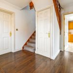 Spacious hallway leading to kitchen with wooden stairs.