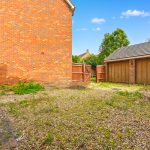 Brick courtyard with wooden garage and open gate.