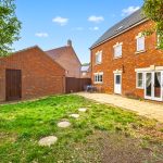 Spacious garden with red brick house and patio.