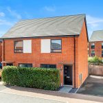 Modern red brick house with solar panels visible.