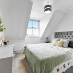 Modern bedroom with stylish decor and large window.