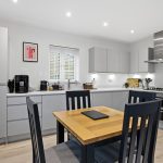 Modern kitchen with dining table and appliances.
