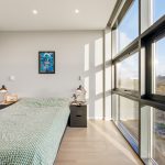 Modern bedroom with large windows and city view.