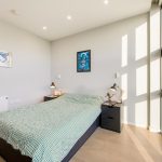 Modern bedroom with large window and desk lamps.
