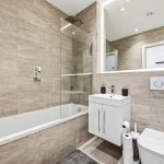Modern bathroom with tiled walls and bathtub.