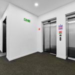 Hallway with elevators and fire exit sign.