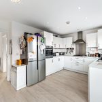 Modern white kitchen with stainless steel appliances.