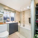 Modern bathroom with shower, sink, and storage shelves.
